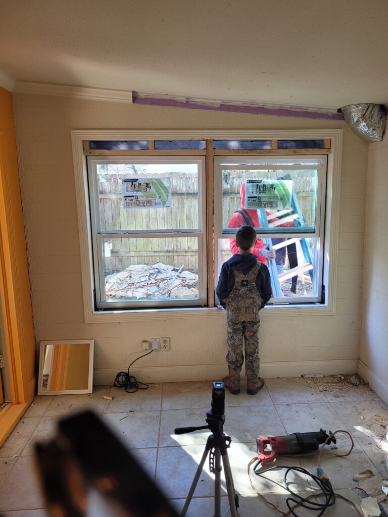 boy looking out window of old house